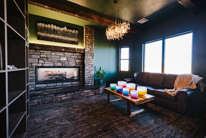 Stone-clad fireplace with a recessed linear firebox, exposed wood beams, and a built-in shelving unit