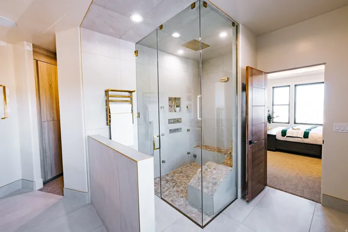 Glass-enclosed shower with a pebble floor, integrated bench, and multiple shower heads