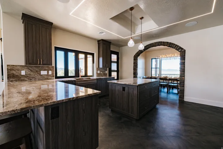 Spacious kitchen featuring dark wood-finish cabinetry, a large center island, and stone countertops