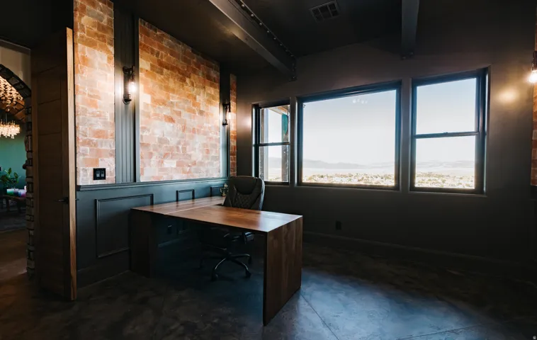 Exposed brick accent wall, wainscoting, sconce lighting, expansive windows, and polished concrete flooring
