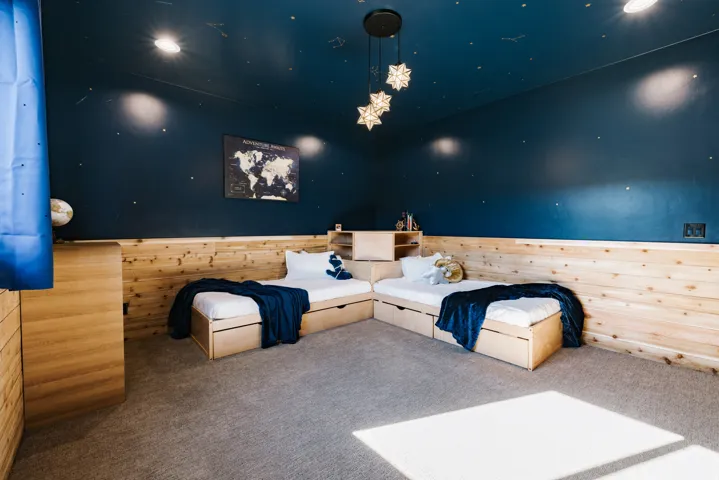 Built-in wood-finish bed frames with integrated storage, wood-paneled wainscoting, and recessed ceiling lighting