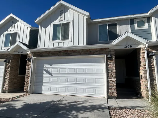 Multi-level exterior with board and batten siding, stone facade accents, white garage door, and entry porch with overhead lighting