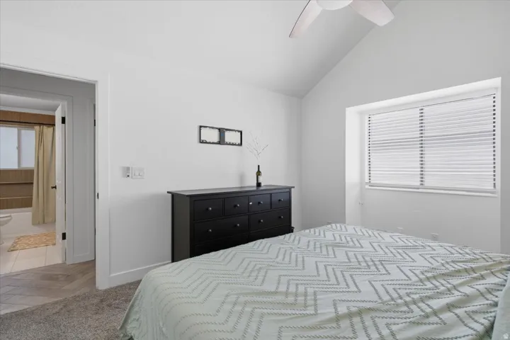 Vaulted ceilings with a ceiling fan, window with blinds, and white walls