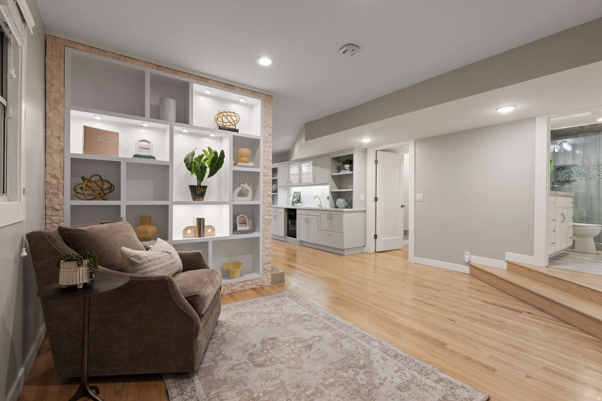Built-in shelving with integrated lighting, wood-finish flooring, recessed lighting, and wet bar