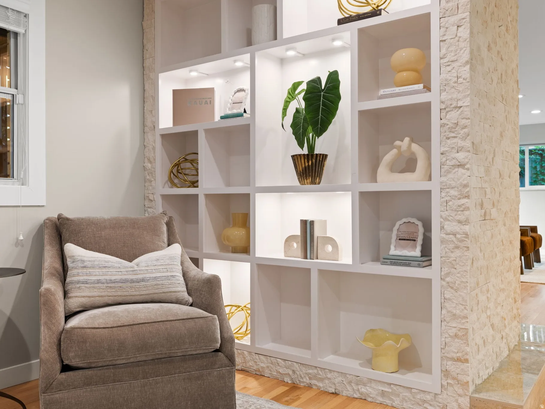 Built-in shelving with integrated lighting, wood-finish flooring, and a stone-clad architectural feature