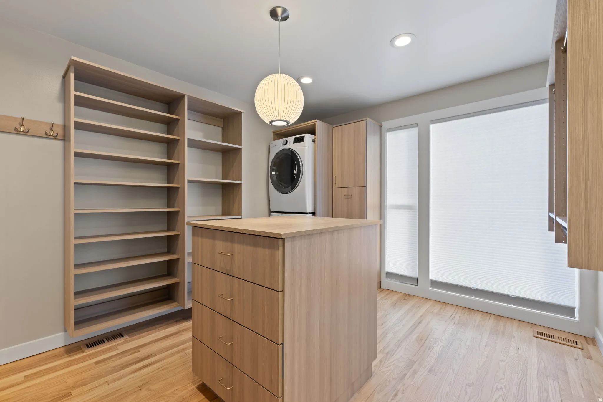 Primary closet with expansive storage space, stackable washer & dryer and central island