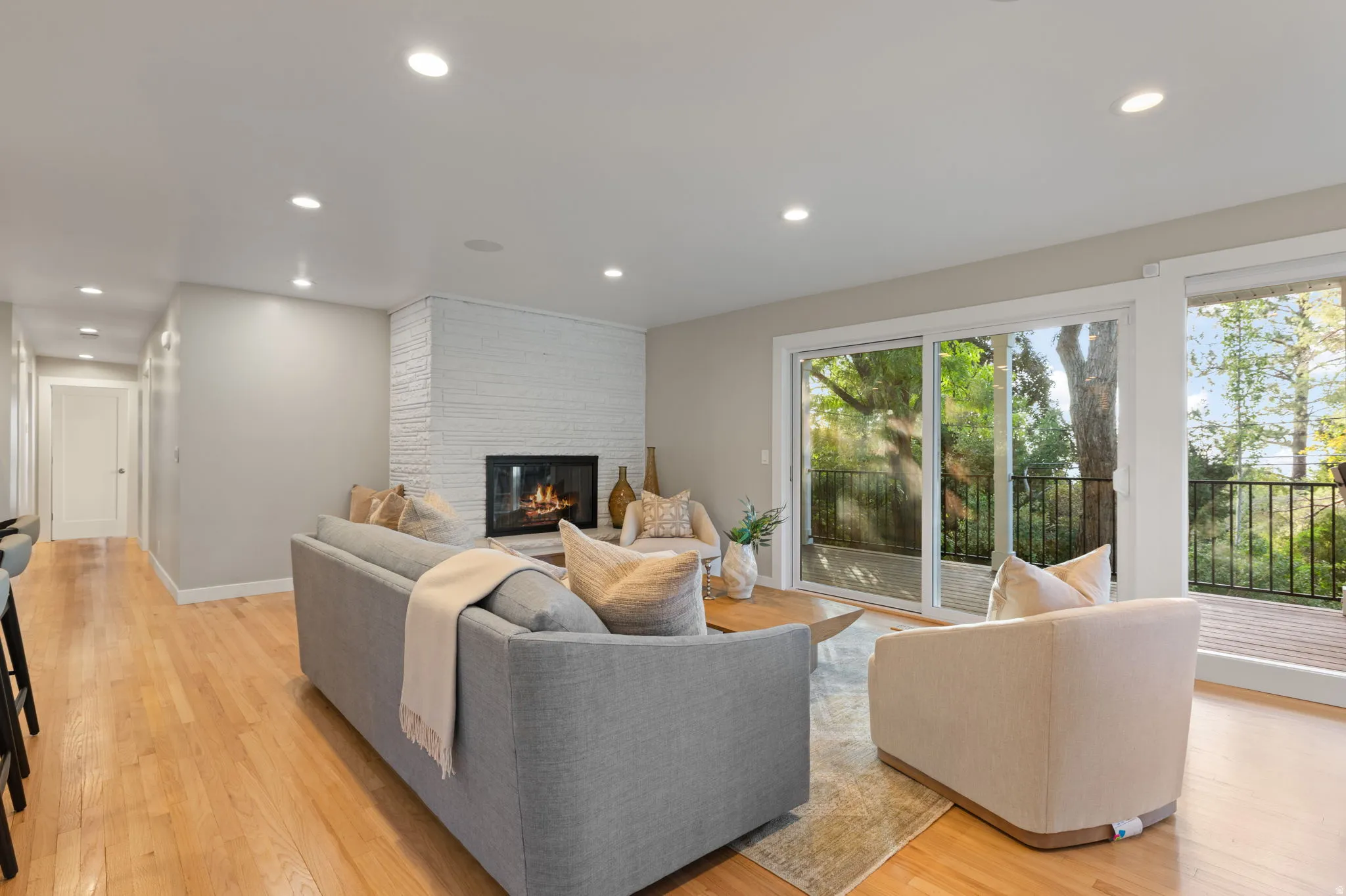 Living room featuring hardwood flooring, contemporary gas fireplace and lush backdrop