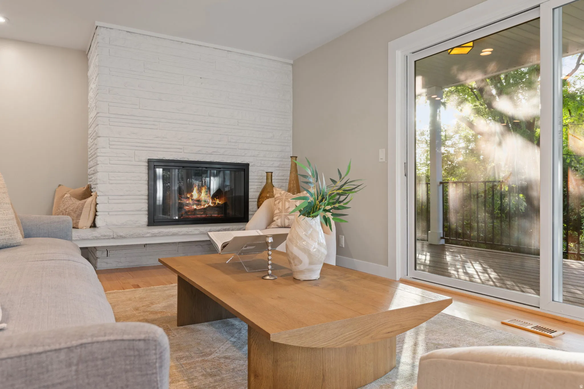 Living room featuring hardwood flooring, contemporary gas fireplace and lush backdrop
