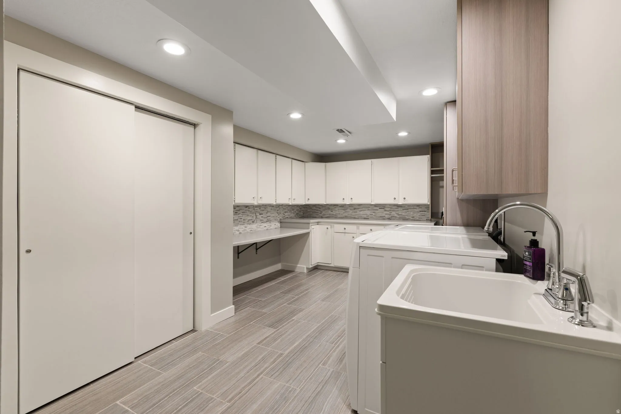 Laundry room with work sink and ample storage space