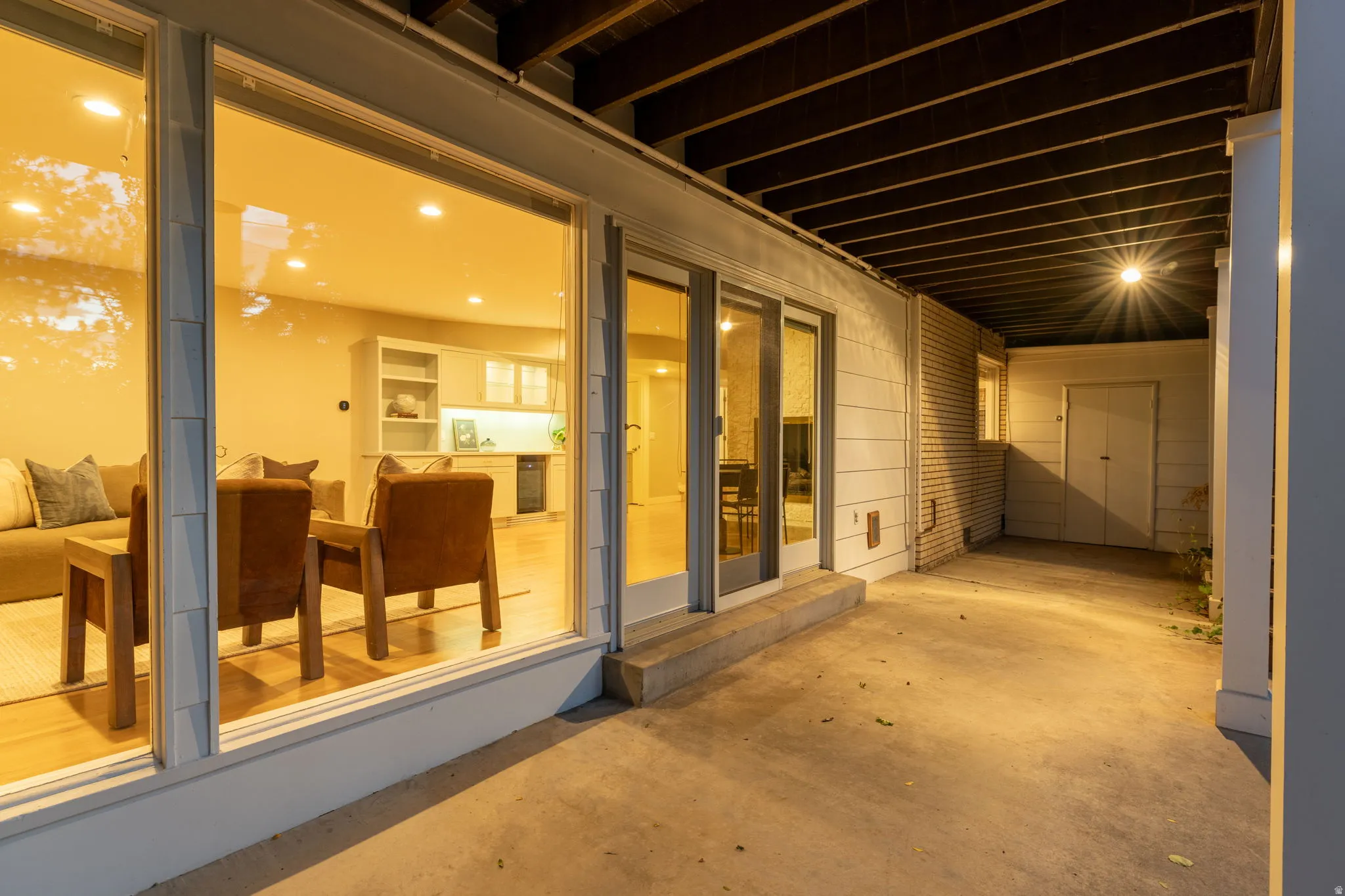 Spacious concrete patio with floor to ceiling windows and walkout to backyard landscaping