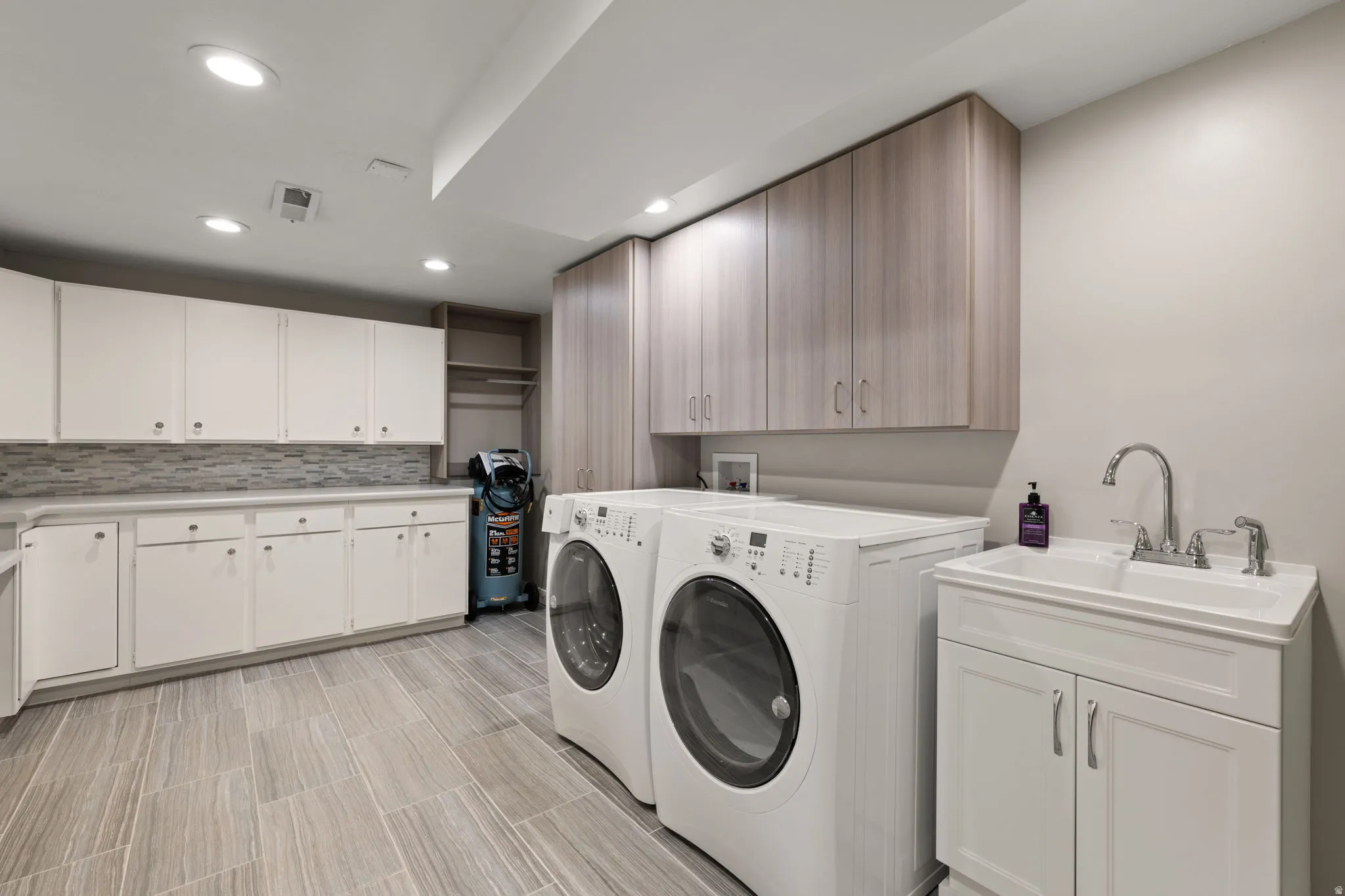 Laundry room with work sink and ample storage space