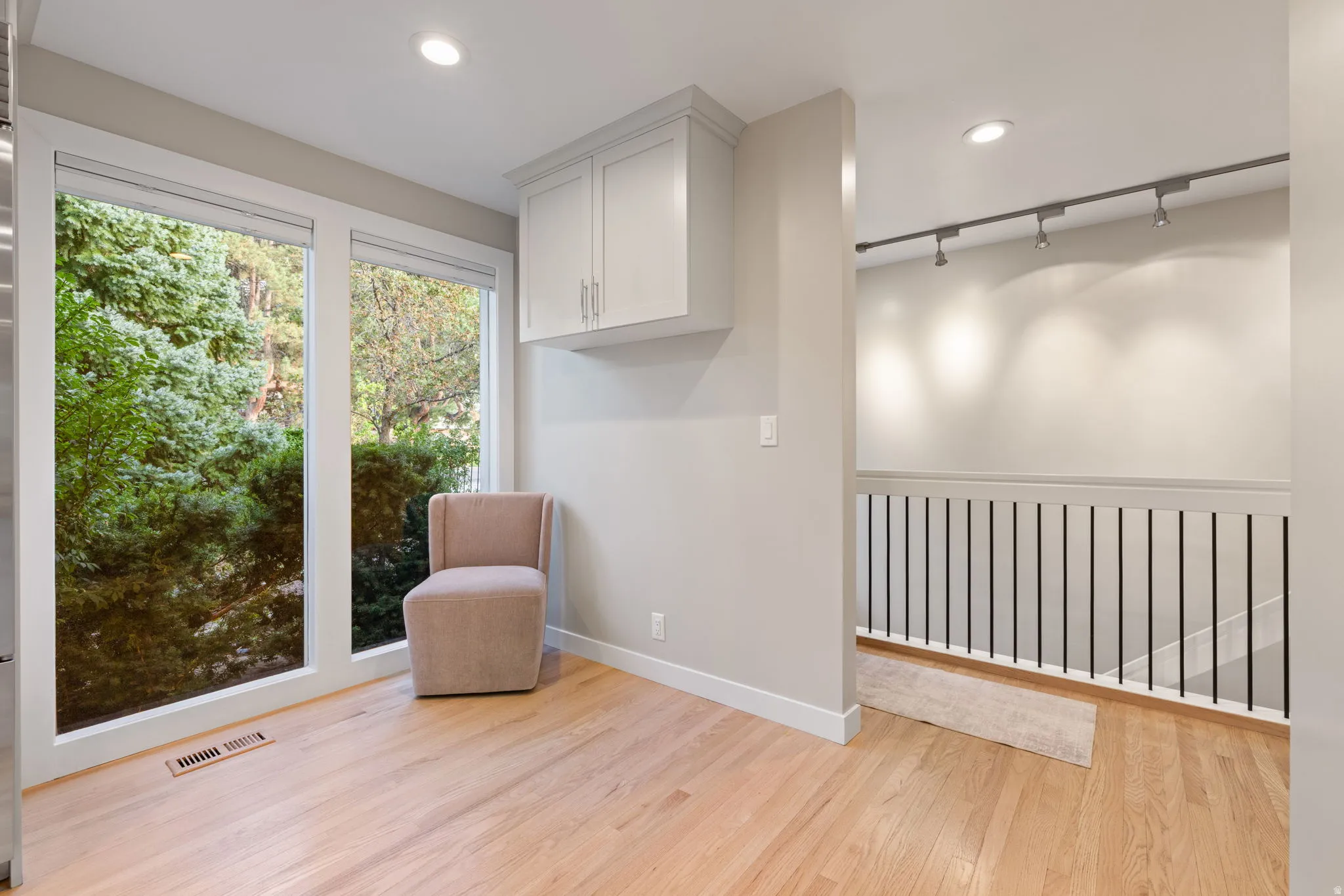 Hardwood flooring throughout, recessed lighting, built-in cabinetry, large windows, and a black metal railing