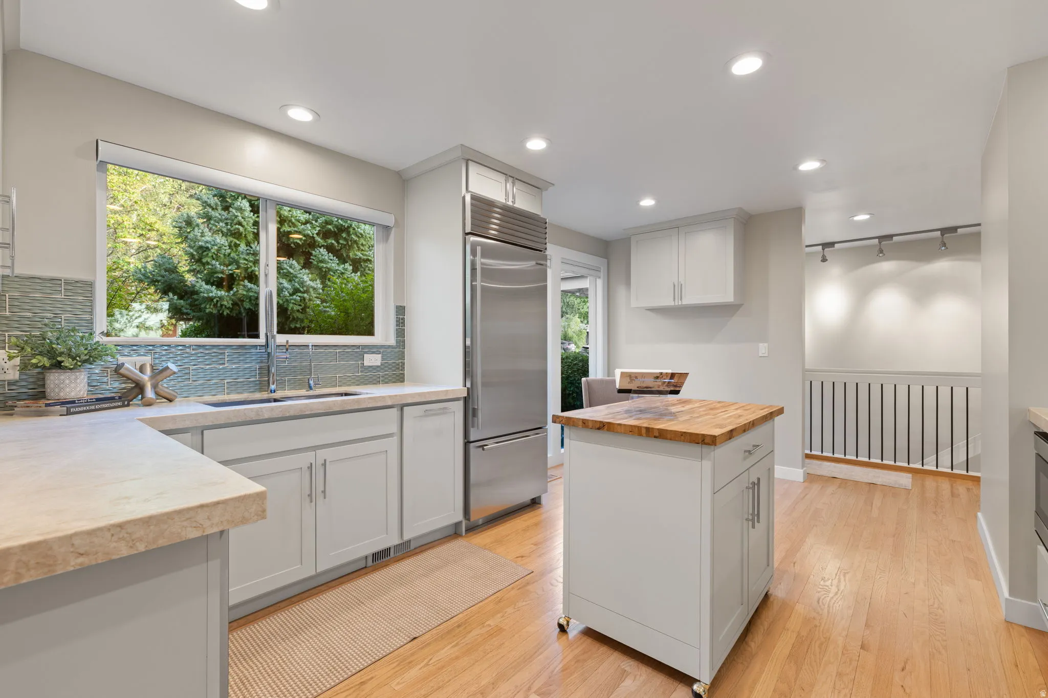 Contemporary kitchen with chef caliber appliances, Taj Mahal quartzite countertops, chrome plumbing fixtures and light, updated cabinetry