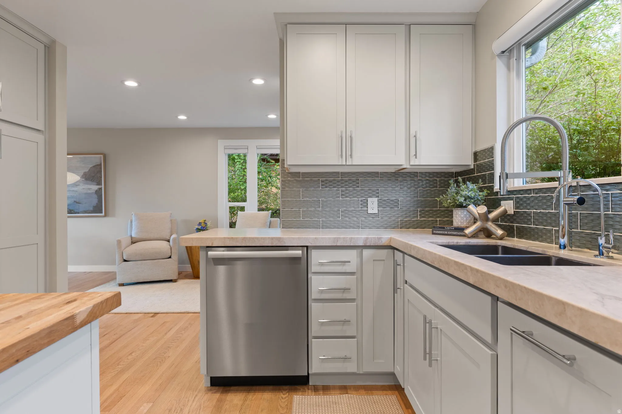 Contempoery cabinetry with brushed nickel hardware, stainless steel dishwasher, dual basin sink with gooseneck faucet and Taj Mahal quartzite countertops