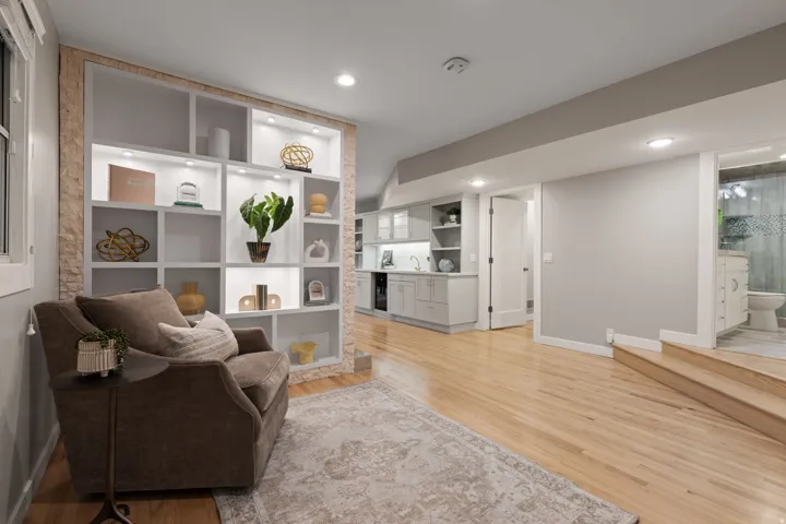 Built-in shelving with integrated lighting, wood-finish flooring, recessed lighting, and wet bar