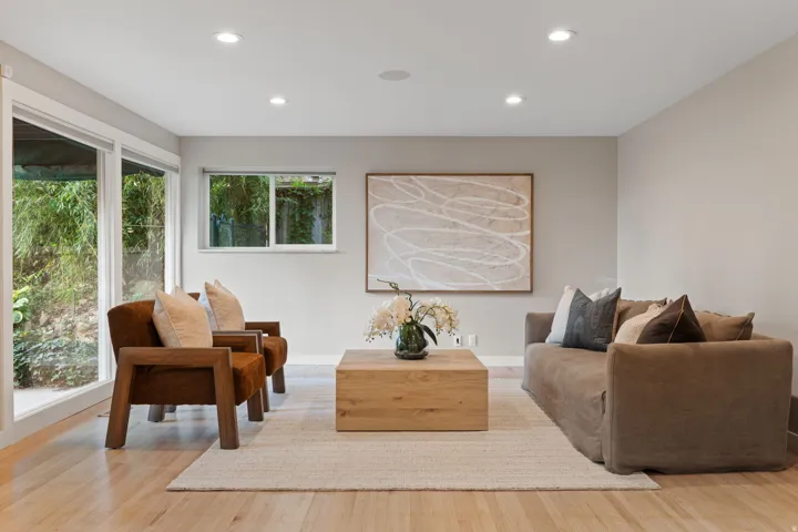 Lower level living room with hardwood flooring, floor to ceiling windows and walkout