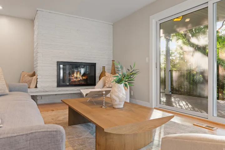 Living room featuring hardwood flooring, contemporary gas fireplace and lush backdrop