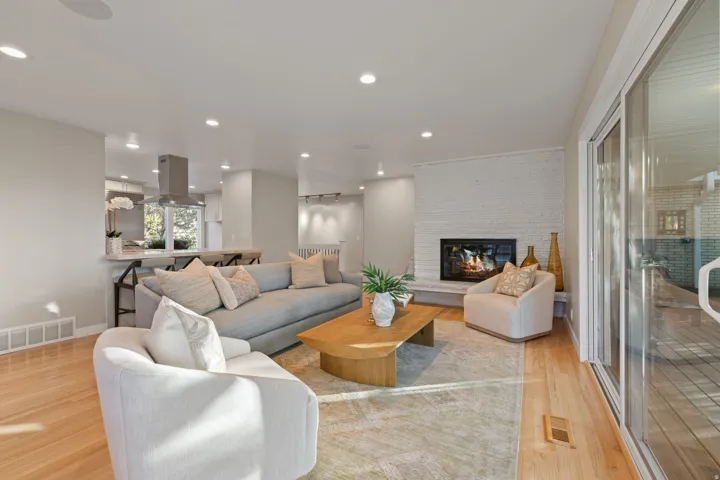 Living room featuring hardwood flooring, contemporary gas fireplace and lush backdrop