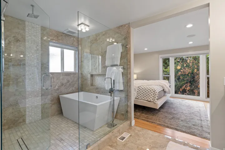 Walk-in shower with full glass enclosure, rain shower head, and mosaic tile accent