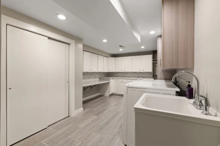 Laundry room with work sink and ample storage space