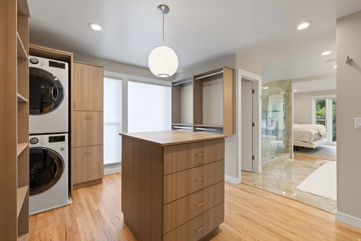 Primary closet with expansive storage space, stackable washer & dryer and central island