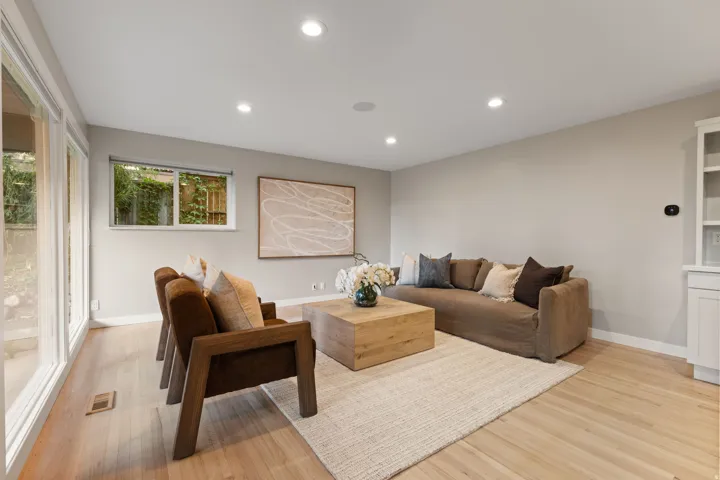 Lower level living room with hardwood flooring, floor to ceiling windows and walkout