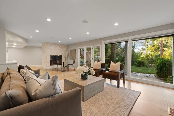 Lower level living room with hardwood flooring, floor to ceiling windows and walkout
