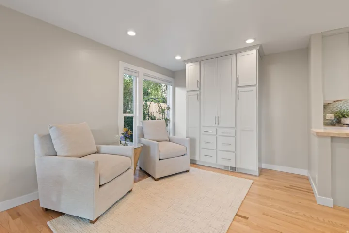 Sitting area off kitchen with hardwood flooring, floor to ceiling windows and light built-in cabinetry