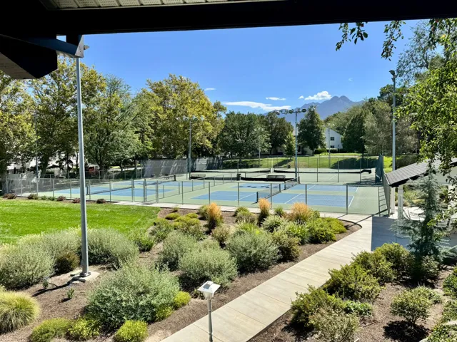 Multiple tennis courts, manicured landscaping, paved pathways, and a mountain backdrop