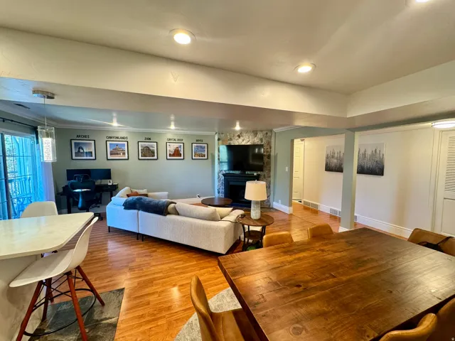 Recessed lighting throughout, wood-finish flooring, stone-clad fireplace surround, and a built-in kitchen island with a light-toned countertop