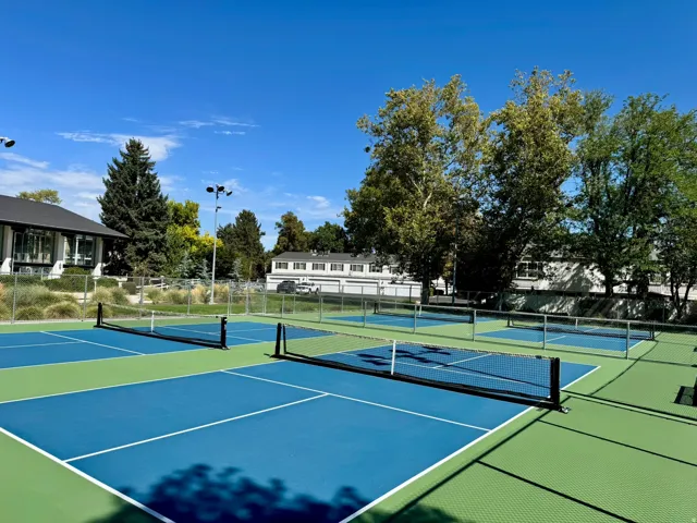 Multiple pickleball courts with blue and green surfacing, court nets, and perimeter fencing