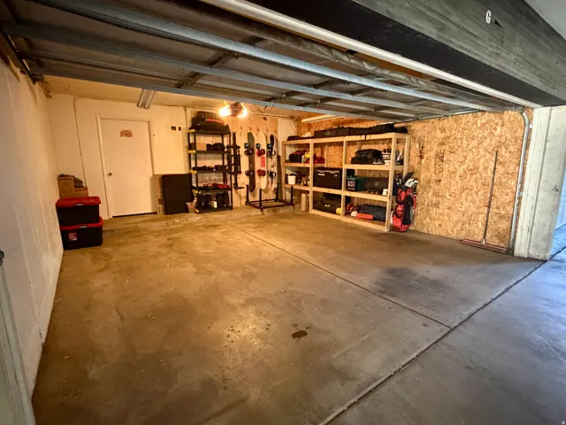 Concrete flooring, exposed ceiling beams, built-in shelving, white painted walls, and an interior access door