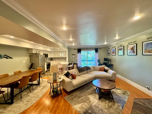 Open-concept living area with wood-finish flooring, recessed lighting, and crown molding