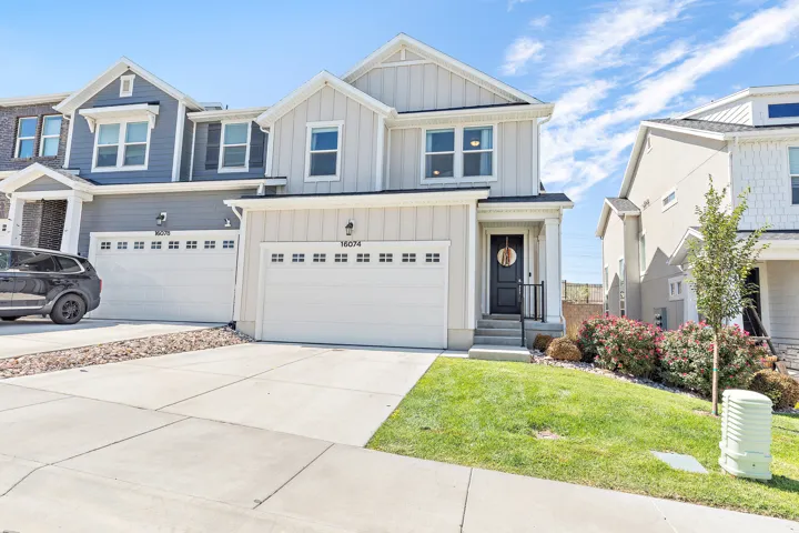 Contemporary two-story exterior with vertical siding, attached two-car garage, concrete driveway, and a welcoming front entrance