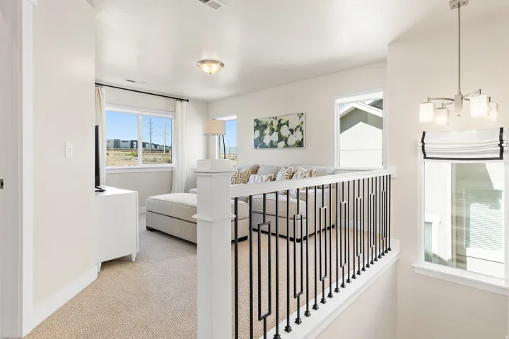 Carpeted landing with white walls and a white railing featuring black metal balusters
