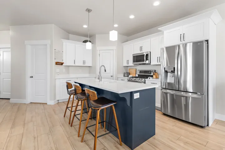 Kitchen featuring a center island with countertop seating, stainless steel appliances, white cabinetry, and wood-finish flooring