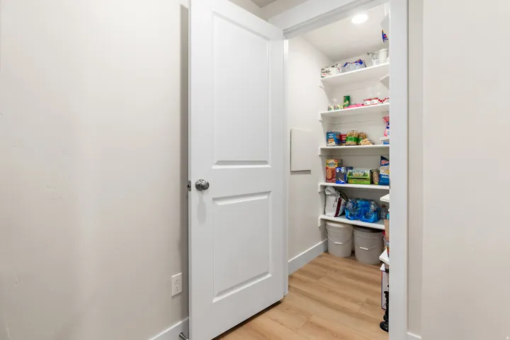 White paneled door with a brushed nickel knob, recessed lighting, and wood-finish flooring