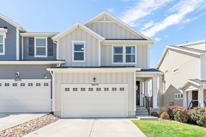 Two-story residence featuring a front-facing attached garage, a covered entryway with columns, and a well-maintained lawn