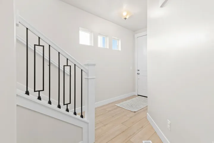 Staircase with modern metal balusters, wood-finish flooring, and recessed wall windows
