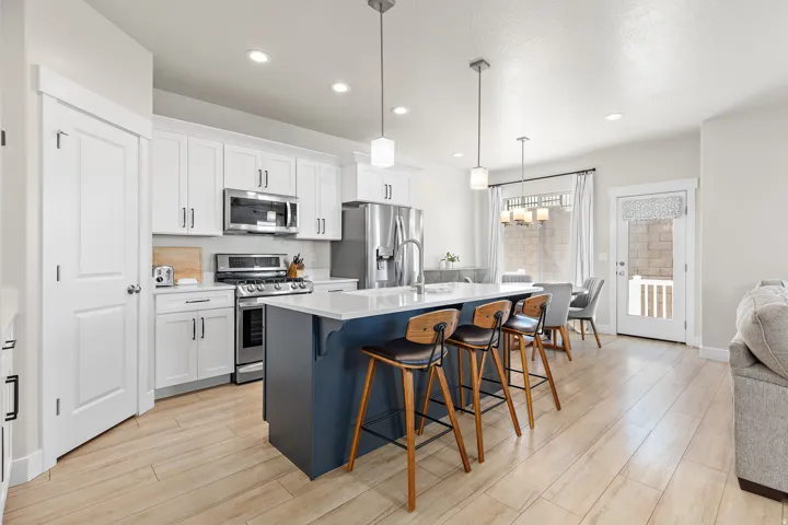Kitchen featuring stainless steel appliances, white cabinetry, a large island with a countertop, wood-finish flooring, and recessed lighting