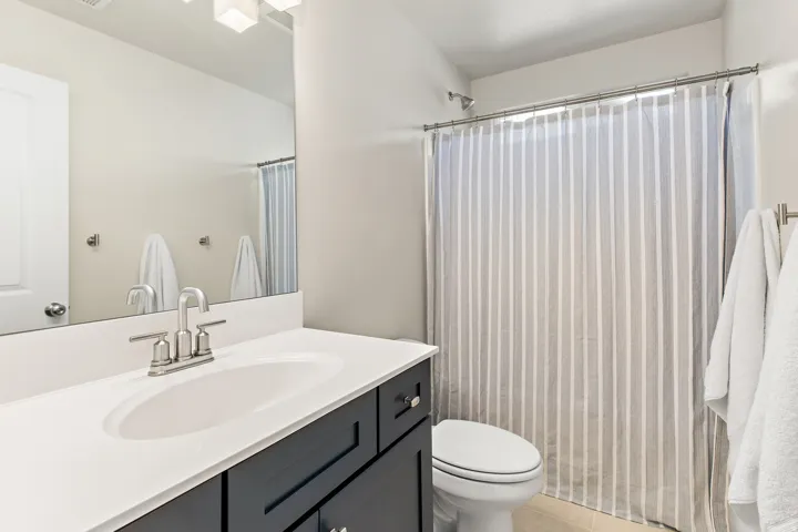 Bathroom featuring a vanity with a white countertop, undermount sink, and dark cabinetry