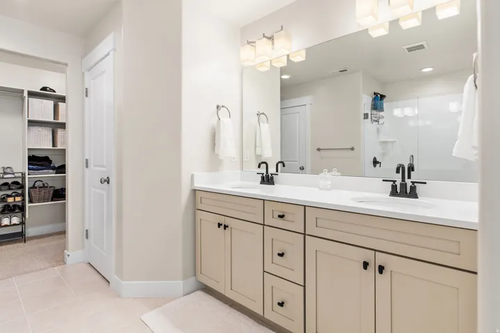 Dual vanities with white countertops, matte black fixtures, and light wood-tone cabinetry
