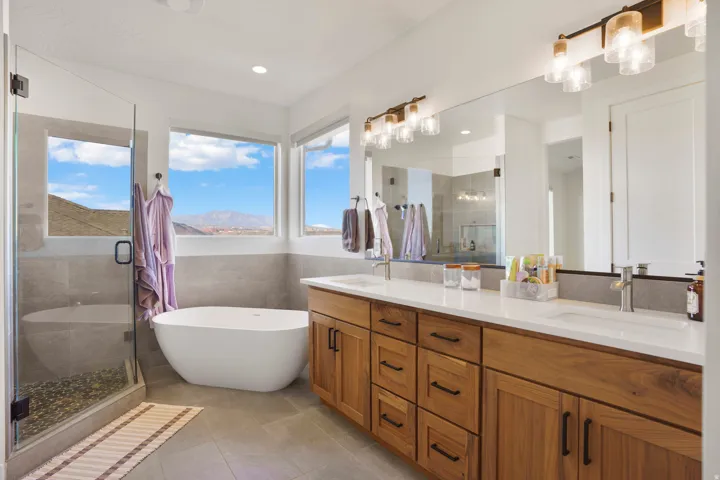 Primary bathroom with dual sink vanity, wood-finish cabinetry and white countertops