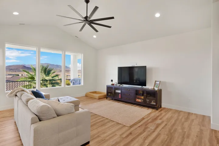 Vaulted ceiling with a contemporary ceiling fan, recessed lighting, expansive windows, and wood-finish flooring