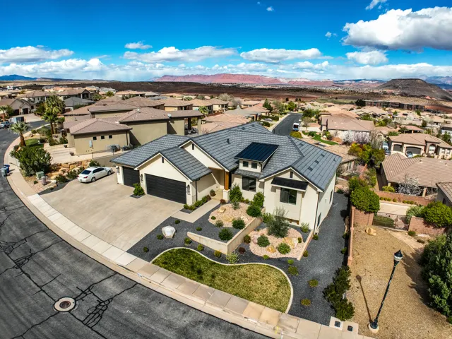 Aerial view - modern stucco exterior with a tiled roof, integrated solar panels, and an attached three-car garage