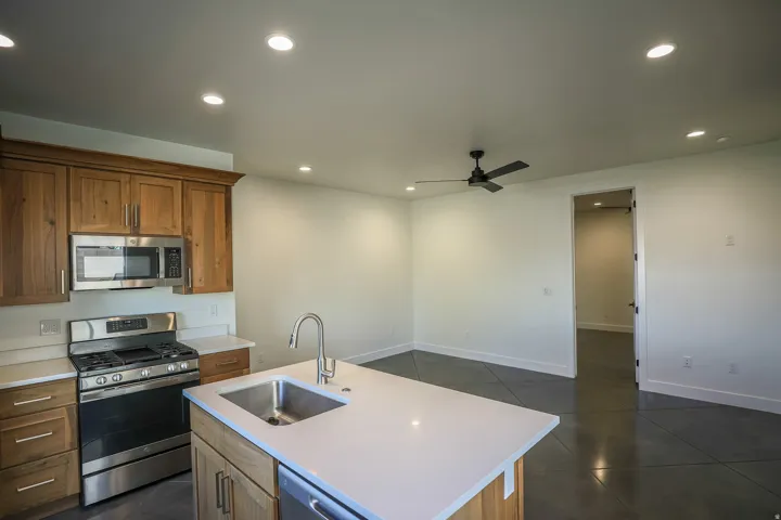 ADU - Kitchen featuring wood cabinetry, stainless steel appliances, and an island with an undermount sink