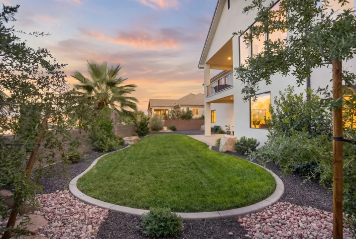 Landscaped backyard with a manicured lawn, concrete curbing, and decorative rock