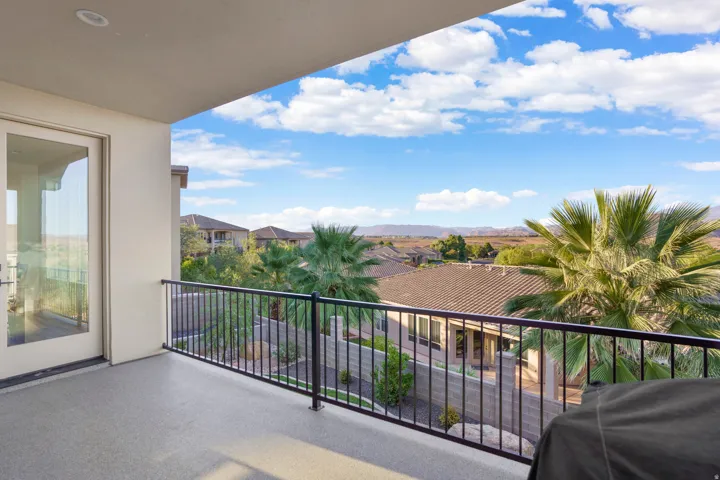 Expansive balcony featuring a glass-paned door, black metal railing, and recessed ceiling lighting