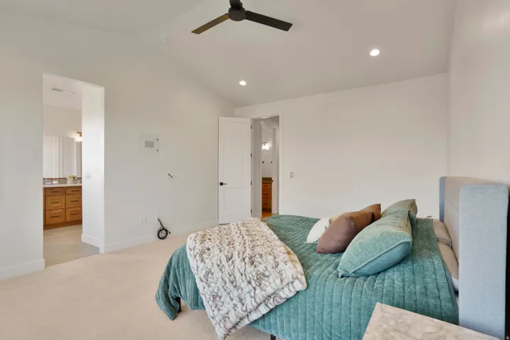Primary bedroom with vaulted ceiling, a ceiling fan, recessed lighting, and soft carpeting