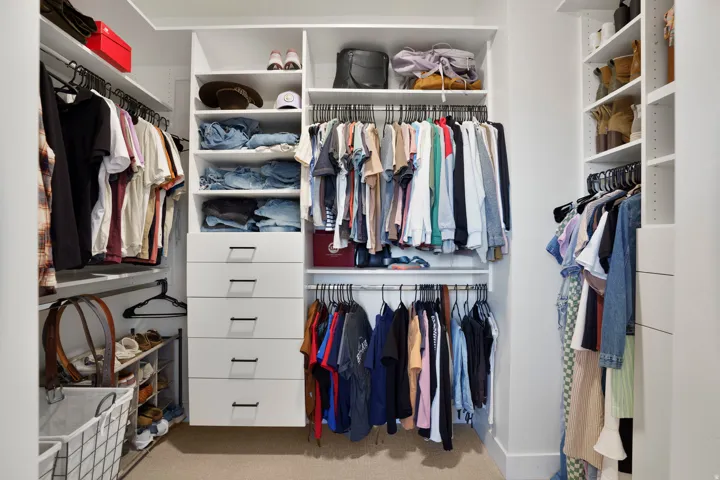 Primary bedroom closet - custom walk-in closet system featuring multiple shelves, hanging rods, and built-in drawers with dark hardware
